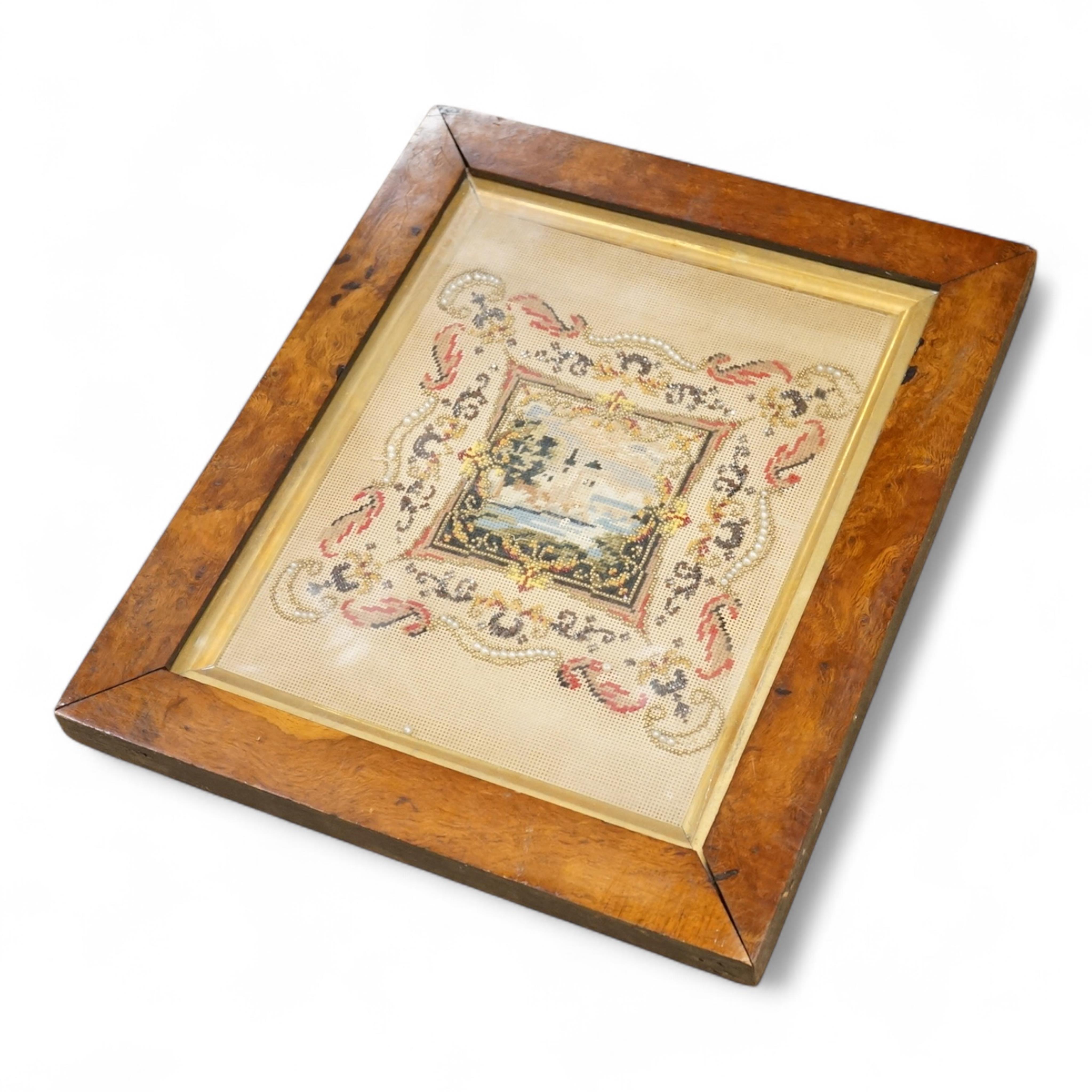 A framed 19th century Berlin bead worked embroidery, worked as a small cartouche of a moated castle with a decorative border, overall 30cm high